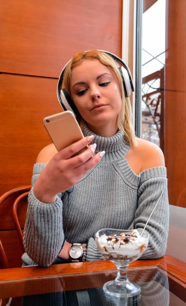 Social Listening ragazza con cuffie e cellulare al bar
