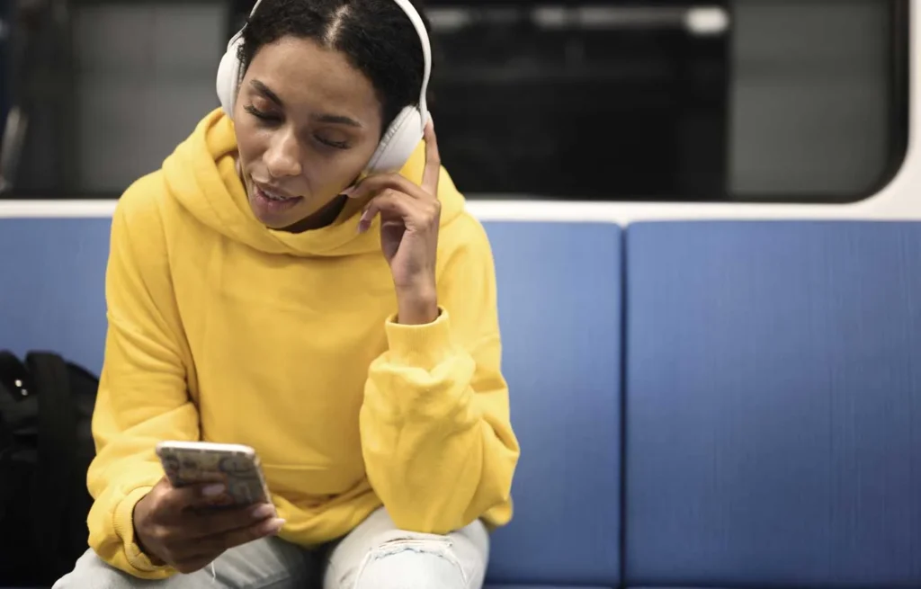 Social Listening ragazza con cuffie e cellulare in metro