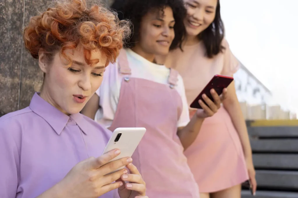 Creare una Community Intorno al Tuo Brand 8 Community online tre ragazze con il cellulare in mano