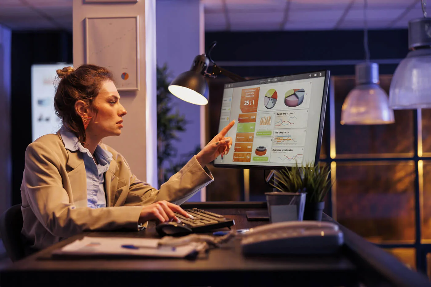 Strategie di Prezzo donna che indica un grafico sullo schermo del computer seduta al posto di lavoro