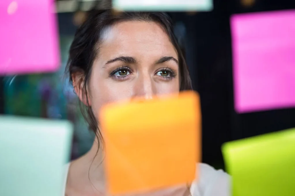 Il Ruolo del Content Manager 1 Content Manager ragazza che guarda dei post-it appesi sulla lavagna trasparente