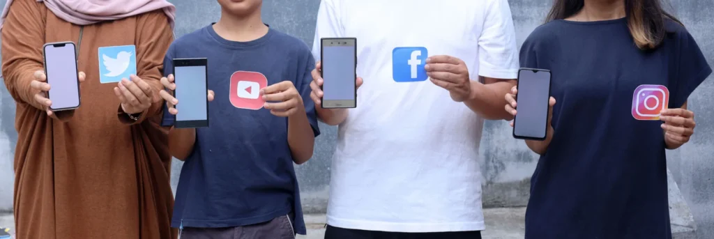 Strategie di Engagement sui Social Media 3 Engagement sui Social Media gruppo di giovani con un cellulare su una mano e una icona social nell'altra