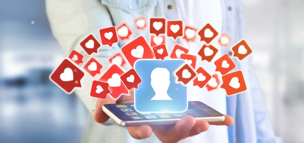 Strategie di Engagement sui Social Media 5 Engagement Social Media persona che regge un cellulare da dove escono delle icone con cuoricini