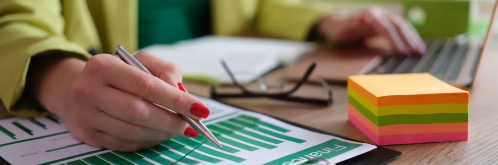 Analisi-del-Comportamento-del-Consumatore-donna-al-lavoro-con-computer-e-grafico-sulla-scrivania