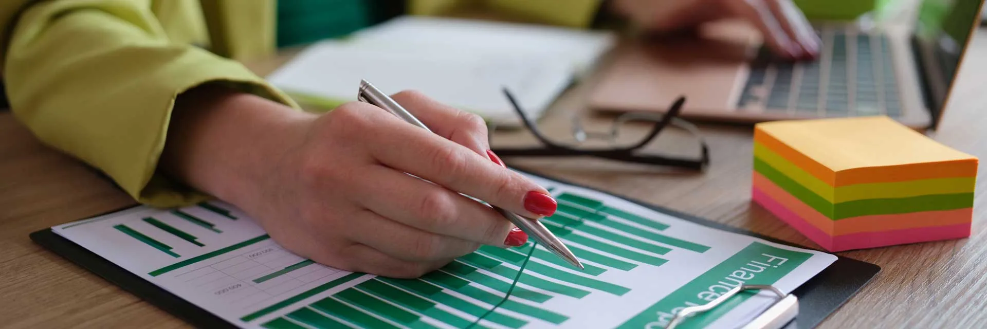 Bilancio e Prospettive mano che scrive sopra dei fogli con grafici