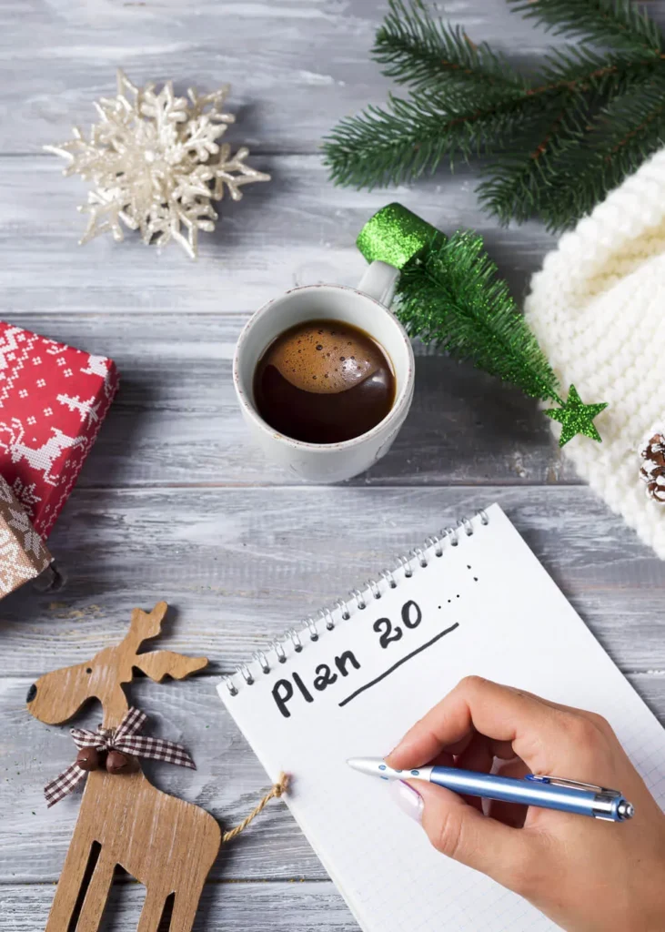 Campagna Natalizia mano femminile che prende appunti su un tavolo con addobbi di natale a lato