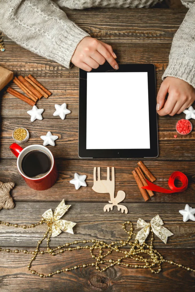 Campagna Natalizia ragazza con tablet seduta a un tavolo con biscotti natalizi