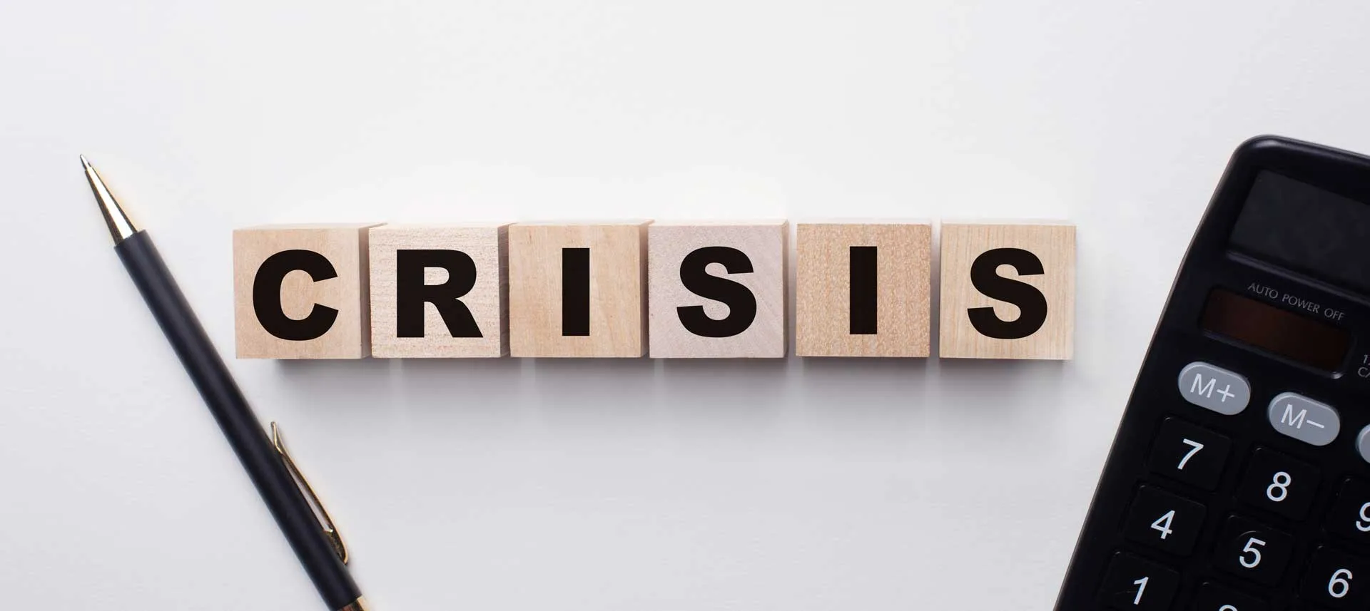 Strategie di Crisis Management 9 Crisis Management composizione di cubetti di legno che formano la scritta Crisis una penna e una calcolatrice