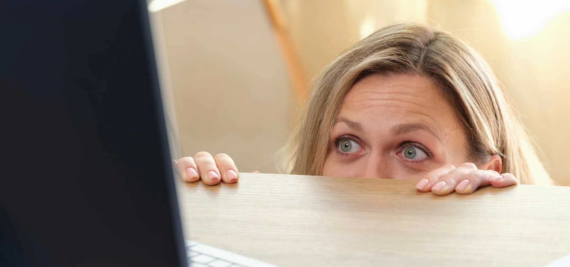 Errori delle PMI nella digital transformation ragazza impaurita che si nasconde dietro il tavolo guardando il computer